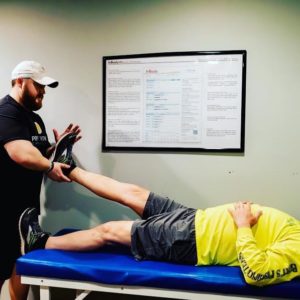 Strength coach at Prime Fitness Clarksville stretching out a man's leg