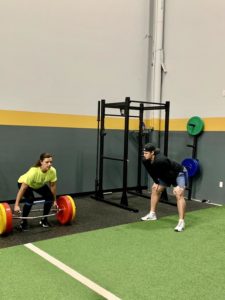 Vinny coaching someone as they lift weights